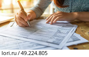 A woman is seated at a table, surrounded by papers and a pen. She appears focused and engaged in the task at hand. Стоковое AI-изображение, AI-художник Данила Большаков / Фотобанк Лори
