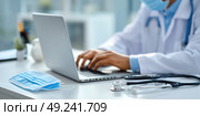 A doctor is typing on a laptop computer while wearing a mask. Стоковое AI-изображение, AI-художник Ярославский Максим / Фотобанк Лори