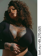 Overweight sensual woman with tattoos strikes a pose for a portrait, showcasing her body art for the camera. Стоковое AI-изображение, AI-художник Данила Большаков / Фотобанк Лори
