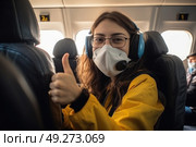 A woman sitting in an airplane seat, wearing a face mask as a precautionary measure. Стоковое AI-изображение, AI-художник Данила Большаков / Фотобанк Лори