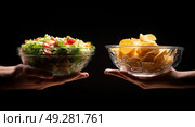 Two people holding up bowls of food, one of which is a salad. Стоковое AI-изображение, AI-художник Ярославский Максим / Фотобанк Лори