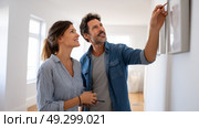 Loving couple standing in their house, hugging and smiling, being happy of buying own lodging. Cheerful young family relocating to new property, free space. Стоковое AI-изображение, AI-художник ALLA YURTAYEVA / Фотобанк Лори