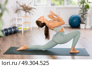 Experienced girl, fitness club teacher, performs crescent moon asana, anjaneyasana. Стоковое фото, фотограф Яков Филимонов / Фотобанк Лори