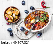 stew meat in plum sauce. meat stew in sauce of autumn plums on a retro background. Стоковое фото, агентство Ingram Publishing / Фотобанк Лори