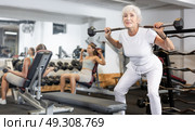 Mature sportswoman doing exercises with a barbell and dumbbells in gym. Стоковое фото, фотограф Яков Филимонов / Фотобанк Лори