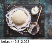 Homemade fresh cheese in  dish and cheesecloth with milk and wooden spoon on rustic background, top view. Стоковое фото, агентство Ingram Publishing / Фотобанк Лори