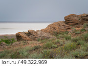 Fancy stones on the slopes of Bolshoe Bogdo Mountain and the salt lake Baskunchak in the distance on a summer day, Bogdinsko-Baskunchak Nature Reserve, Akhtubinsky district, Astrakhan region, Russia. Стоковое фото, фотограф Ula Ulachka / Фотобанк Лори