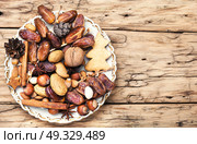 Christmas decorations with nuts, spices and bumps on a plate. Christmas plate with nuts, spices and cedar cone. Стоковое фото, агентство Ingram Publishing / Фотобанк Лори