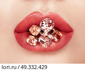 Close up view of Beautiful Woman Lips with Red Lipstick. Open Mouth with white Teeth. Cosmetology, drugstore or Fashion Makeup Concept.  Jewelry dyeing gems. Стоковое фото, агентство Ingram Publishing / Фотобанк Лори
