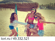 teen best friends girls under thatch umbrella having fun on a beach. Стоковое фото, агентство Ingram Publishing / Фотобанк Лори