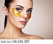 Portrait of Beauty Woman with Eye Patches. Woman Beauty Face with Mask under Eyes. Beautiful Female with natural Makeup and Gold Cosmetics Collagen Patches on Fresh Facial Skin. Стоковое фото, агентство Ingram Publishing / Фотобанк Лори