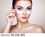Portrait of Beauty Woman with eye Patches showing an effect of Perfect Skin. Beautiful Face of young Woman with clean Fresh Skin and bare shoulders on beige background. Brunette Spa Girl. Стоковое фото, агентство Ingram Publishing / Фотобанк Лори
