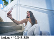 Young latin woman selfie photo smarphone in a white stairway outdoor. Стоковое фото, агентство Ingram Publishing / Фотобанк Лори