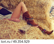 female legs with leather brown on straw bale. female legs with leather brown boots relaxed on straw bale barn. Стоковое фото, агентство Ingram Publishing / Фотобанк Лори
