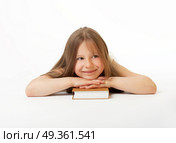 A smiling girl lays on a white background having put a head on the book. The happy clever girl. Стоковое фото, агентство Ingram Publishing / Фотобанк Лори