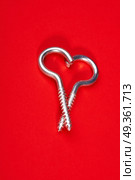 Two spiral bolts laying in the form of heart on a red background. Steel heart. Стоковое фото, агентство Ingram Publishing / Фотобанк Лори