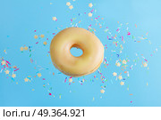 flying doughnuts on blue. one flying sweet doughnut in glaze with sprincles on blue. Стоковое фото, агентство Ingram Publishing / Фотобанк Лори