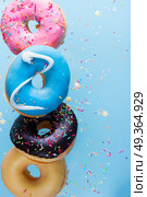 flying doughnuts on blue. flying doughnuts border - mix of multicolored sweet donuts with sprinkles on blue background. Стоковое фото, агентство Ingram Publishing / Фотобанк Лори