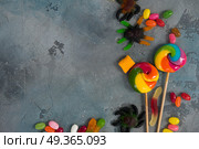 Colorful halloween candies on stone. Trick and treat - halloween scary candies border on stone with copy space. Стоковое фото, агентство Ingram Publishing / Фотобанк Лори