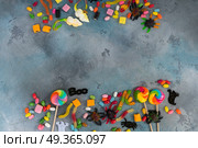 Colorful halloween candies on stone. Trick and treat sweets - colorful halloween candies frame on gray stone with copy space. Стоковое фото, агентство Ingram Publishing / Фотобанк Лори