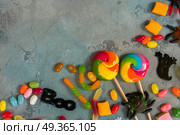 Colorful halloween candies on stone. Trick and treat - halloween candies border on gray stone with copy space. Стоковое фото, агентство Ingram Publishing / Фотобанк Лори