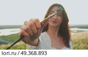 Artist standing in field and painting landscape raises her brush and closes her eyes to create perfect proportions of objects in her painting. Close up. Стоковое видео, видеограф Strunov David / Фотобанк Лори
