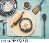 Tasty baking. Dough, rolling pin and bowl with flour and egg on light blue kitchen table background, top view. Стоковое фото, агентство Ingram Publishing / Фотобанк Лори