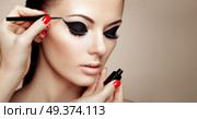 Makeup Artist Applies Eyeshadow. Beautiful Woman Make-up Eye with Black Liner. Fashion Makeup Arrows. Red Nails Perfect Skin. Стоковое фото, агентство Ingram Publishing / Фотобанк Лори
