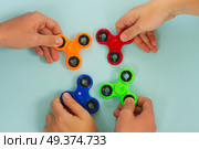 trendy fidget spinners - styled flat lay scene with hands holding colorful generic design spinners on blue. fidget spinner, popular relaxing toy, generic design. Стоковое фото, агентство Ingram Publishing / Фотобанк Лори