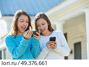 Sister twins having fun with technology mobile smartphone. Стоковое фото, агентство Ingram Publishing / Фотобанк Лори
