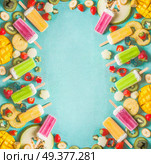 Frame made with colorful Ice cream popsicles with fresh sliced fruits and berries ingredients on light blue background, top view, flat lay. Frozen tropical juices. Homemade ice cream. Стоковое фото, агентство Ingram Publishing / Фотобанк Лори