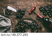 Red wine still life. Wine Glass with  bottle, corkscrew and red grape clusters on wooden rustic background, top view. Стоковое фото, агентство Ingram Publishing / Фотобанк Лори