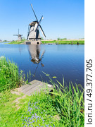 traditional dutch windmill with wooden pier in Kinderdijk at summer day, Netherland. dutch windmill over river waters. Стоковое фото, агентство Ingram Publishing / Фотобанк Лори