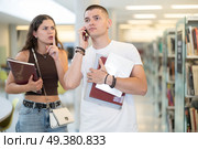 Female library patron makes remark to male student talking on phone. Стоковое фото, фотограф Яков Филимонов / Фотобанк Лори