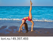 acrobatic gymnastics bikini girl in a beach blue shore at summer. Стоковое фото, агентство Ingram Publishing / Фотобанк Лори