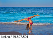 acrobatic gymnastics bikini girl in a beach blue shore at summer. Стоковое фото, агентство Ingram Publishing / Фотобанк Лори