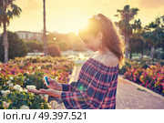 Girl portrait taking photos to a rose flower with smarphone. Стоковое фото, агентство Ingram Publishing / Фотобанк Лори