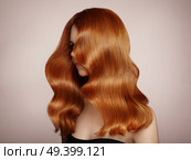 Redhead Girl with Long Healthy and Shiny Curly Hair. Care and Beauty. Beautiful Model Woman with Wavy Hairstyle. Make-Up and Black Dress. Стоковое фото, агентство Ingram Publishing / Фотобанк Лори