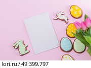 Eater handmade cookies on pink background with copy space on paper note. Easter scene with colored eggs. Стоковое фото, агентство Ingram Publishing / Фотобанк Лори