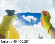 Spring cleaning - someones hands in yellow gloves with spray and ruber cleaning window. Spring cleaning concept. Стоковое фото, агентство Ingram Publishing / Фотобанк Лори