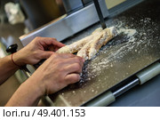 Close-up of male butcher cutting ham bones in a cutting machine inside a butcher shop. Стоковое фото, агентство Ingram Publishing / Фотобанк Лори