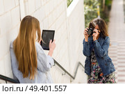 Two young tourist women taking photographs with digital tablet and analogic reflex camera. Travelers concept. Стоковое фото, агентство Ingram Publishing / Фотобанк Лори