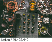 Confectionery or patisserie concept. Preparation of pralines with prunes soaked in rum and stuffed with nuts, marshmallow and pistachio on dark table background with chocolate and ingredients. Стоковое фото, агентство Ingram Publishing / Фотобанк Лори