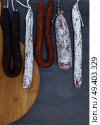 Cured meat and sausages hanging on dark wooden background. Cured meat and sausages. Стоковое фото, агентство Ingram Publishing / Фотобанк Лори