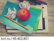 Apple with school supplies on white wooden table, top view, retro toned. Apple with school supplies. Стоковое фото, агентство Ingram Publishing / Фотобанк Лори