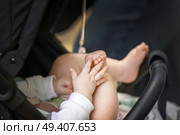 Baby in stroller demonstrates early development stage - hand-foot interaction, a precursor to crawling. Стоковое фото, фотограф Татьяна Степанищева / Фотобанк Лори