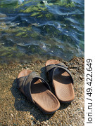 A pair of mens leather sandals on water’s edge by sea. Стоковое фото, агентство Ingram Publishing / Фотобанк Лори