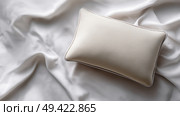 Soft beige pillow resting on smooth, elegant white fabric background. Мягкая бежевая подушка лежит на гладком, элегантном фоне из белой ткани. Стоковое AI-изображение, AI-художник Katsiaryna Repich / Фотобанк Лори