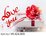Love you text lettering with white gift box, red bow on snow with bokeh and snowfall. Valentines day declaration of love concept. Стоковое фото, агентство Ingram Publishing / Фотобанк Лори