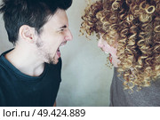Portrait of a natural caucasian couple of young woman with curly blonde hair and man from side, they shout and argue each other. Стоковое фото, агентство Ingram Publishing / Фотобанк Лори